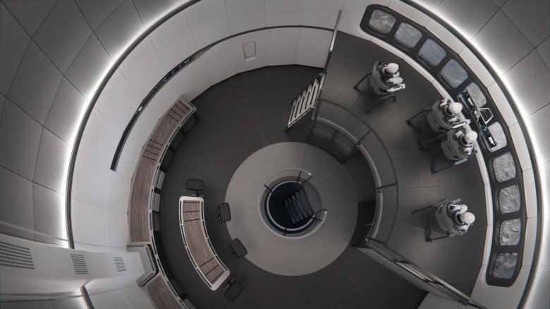 illustration of the cylindrical interior of a spacecraft, showing four astronauts seated near monitors at the right of the screen