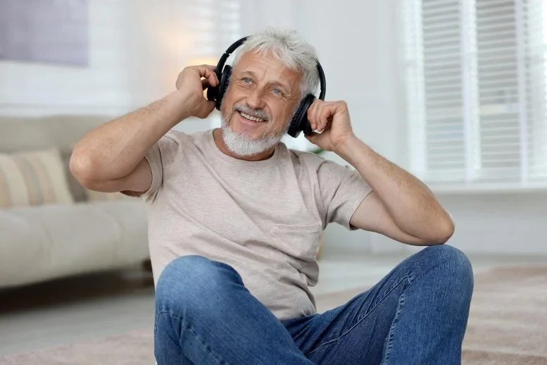 Listening to Music May Cut Dementia Risk by 39%, Study Finds Smiling Senior Man Listening Headphones Music